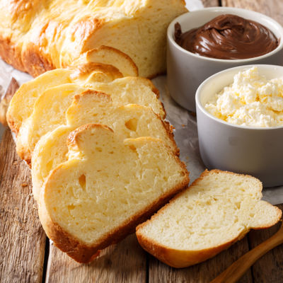 Une brioche tranchée accompagnée de beurre et d'une tartine style Nutella