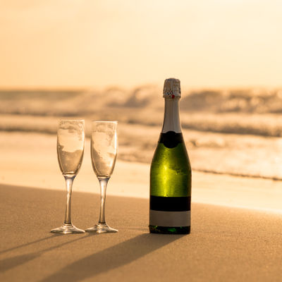 Une bouteille de champagne et 2 coupes sur le sable de la plage