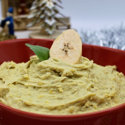 Purée de bananes plantain décorée avec une rondelle de banane et une feuille de basilic.