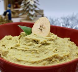 Purée de bananes plantain décorée avec une rondelle de banane et une feuille de basilic.