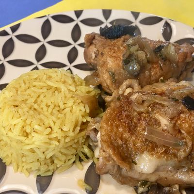 Une assiette avec du poulet à la bière et aux champignons et du riz au curry.