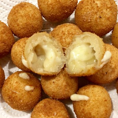 Des petites croquettes de fromage et une croquette coupée avec un cœur fondant au fromage