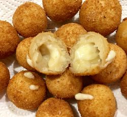 Des petites croquettes de fromage et une croquette coupée avec un cœur fondant au fromage