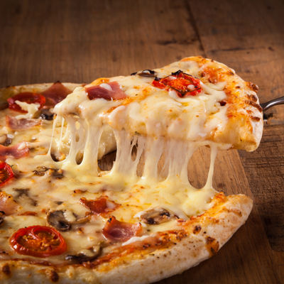 Une pizza maison avec des tomates, champignons, fromage et jambon